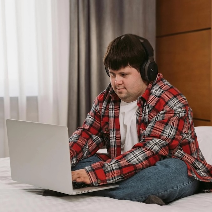 Boy with a laptop sitting on a bed